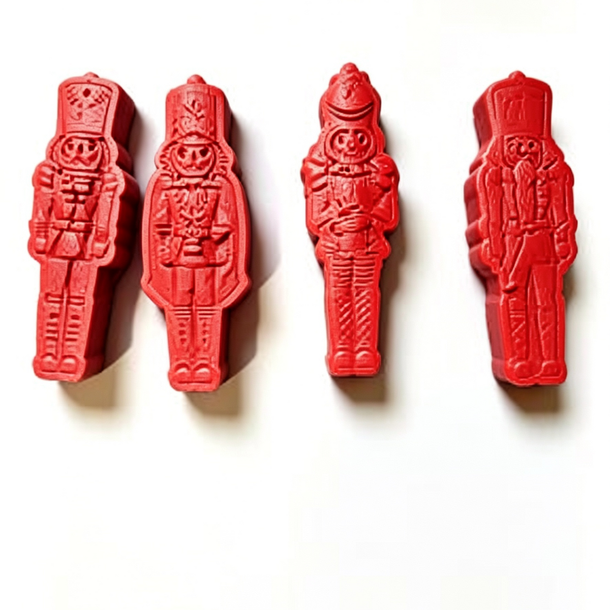 Four red wax melt shaped like soldiers on a white background