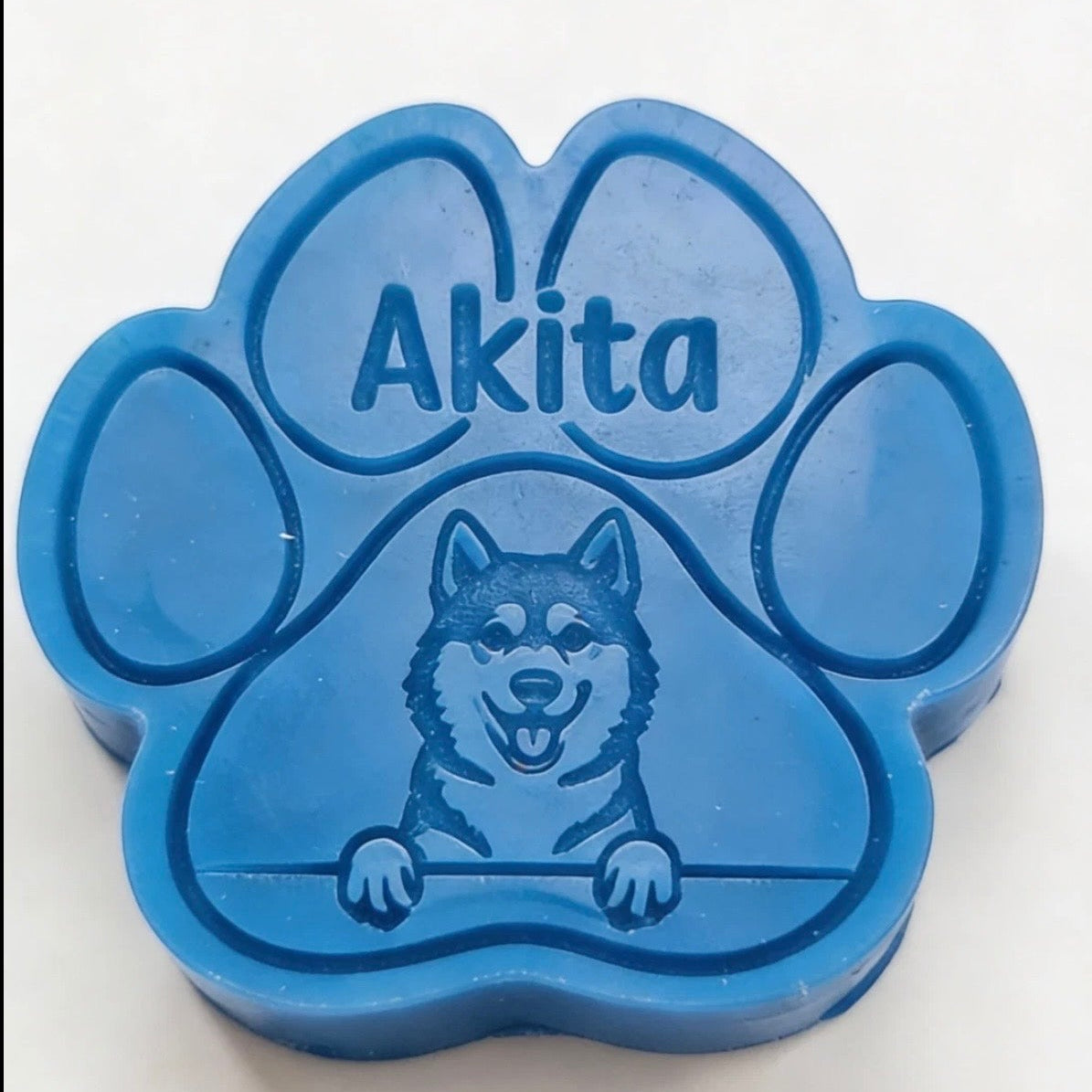 Blue paw-shaped wax melt with 'Akita' and a dog illustration on a white background