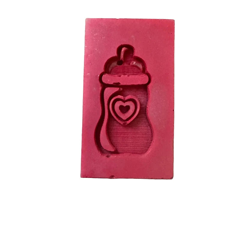 A rectangular pink wax melt with a baby bottle and heart design embossed on the front, isolated on a white background.