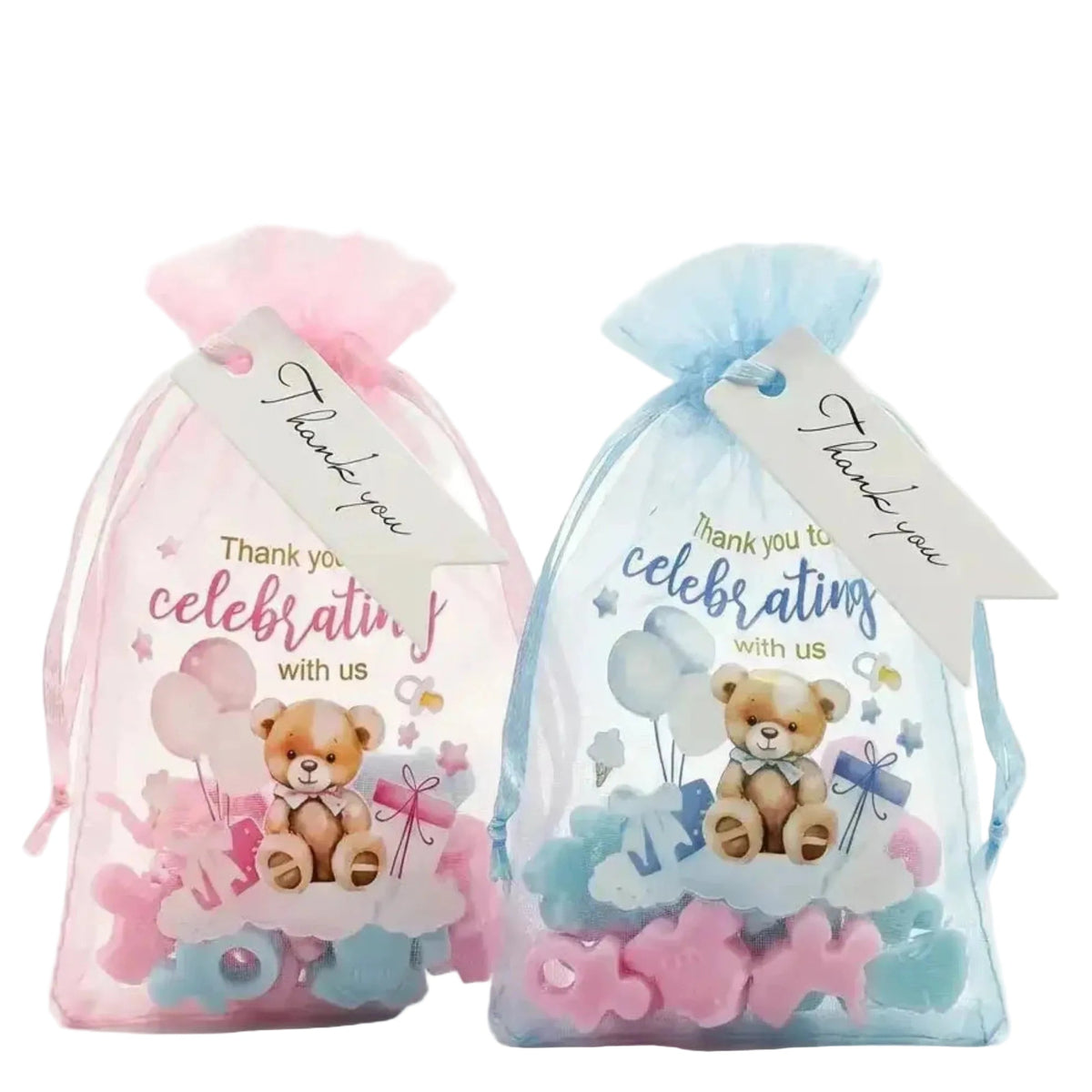 Two sheer mesh favor bags, one pink and one light blue, each containing baby wa melt items and a printed teddy bear gift tag with a 'Thank you' ribbon, on a white background.