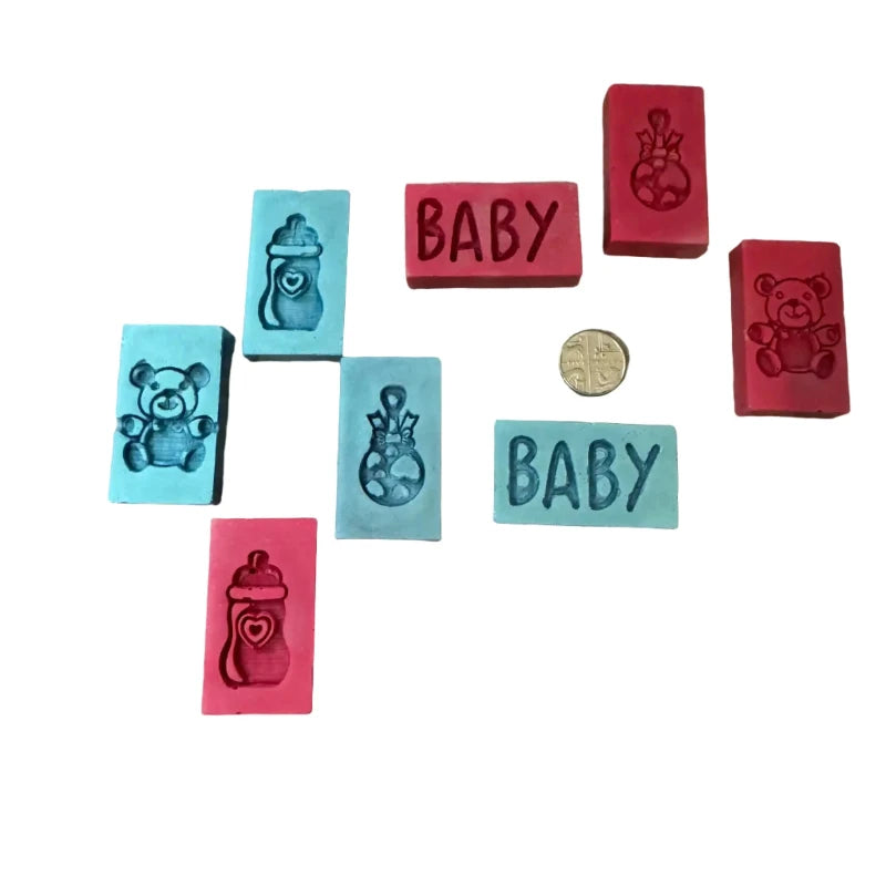 A set of baby-themed wax melts  in pink, red, and light blue, featuring embossed teddy bears, bottles, and the word 'BABY', arranged on a white background with a small coin for scale.