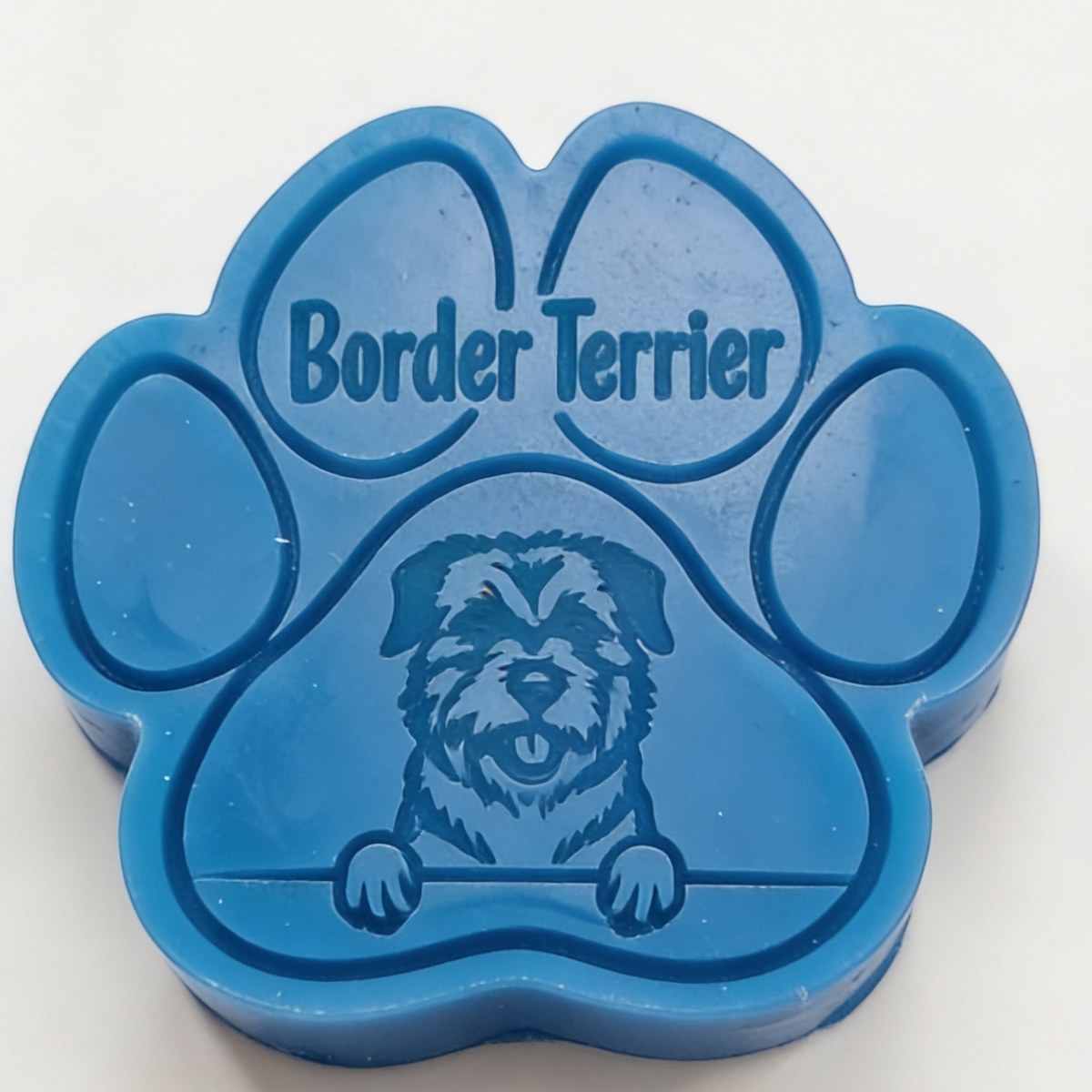 A blue paw-shaped Wax melt featuring an engraved Border Terrier dog illustration and the text 'Border Terrier' on the top pad, photographed on a plain white background.