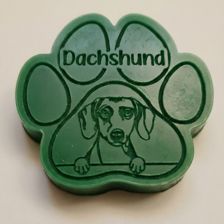Green paw-shaped wax melt with 'Dachshund' text and dachshund illustration on a beige background