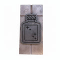 A rectangular metal wall plaque featuring a raised bottle outline with sparkles, mounted on a textured metallic backing against a light beige wall.