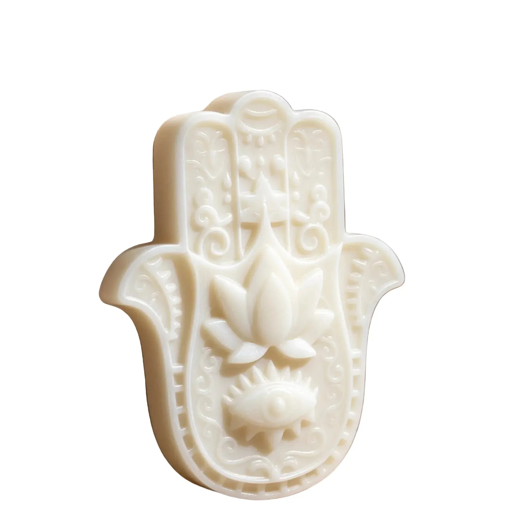 An off-white Hamsa hand soap bar featuring embossed details of a lotus flower, an eye of Providence, and intricate scrollwork, shown on a plain white background. CANDLE