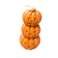 A Halloween-themed candle shaped like three stacked jack-o'-lantern pumpkins, with a white wick at the top, isolated on a white background.