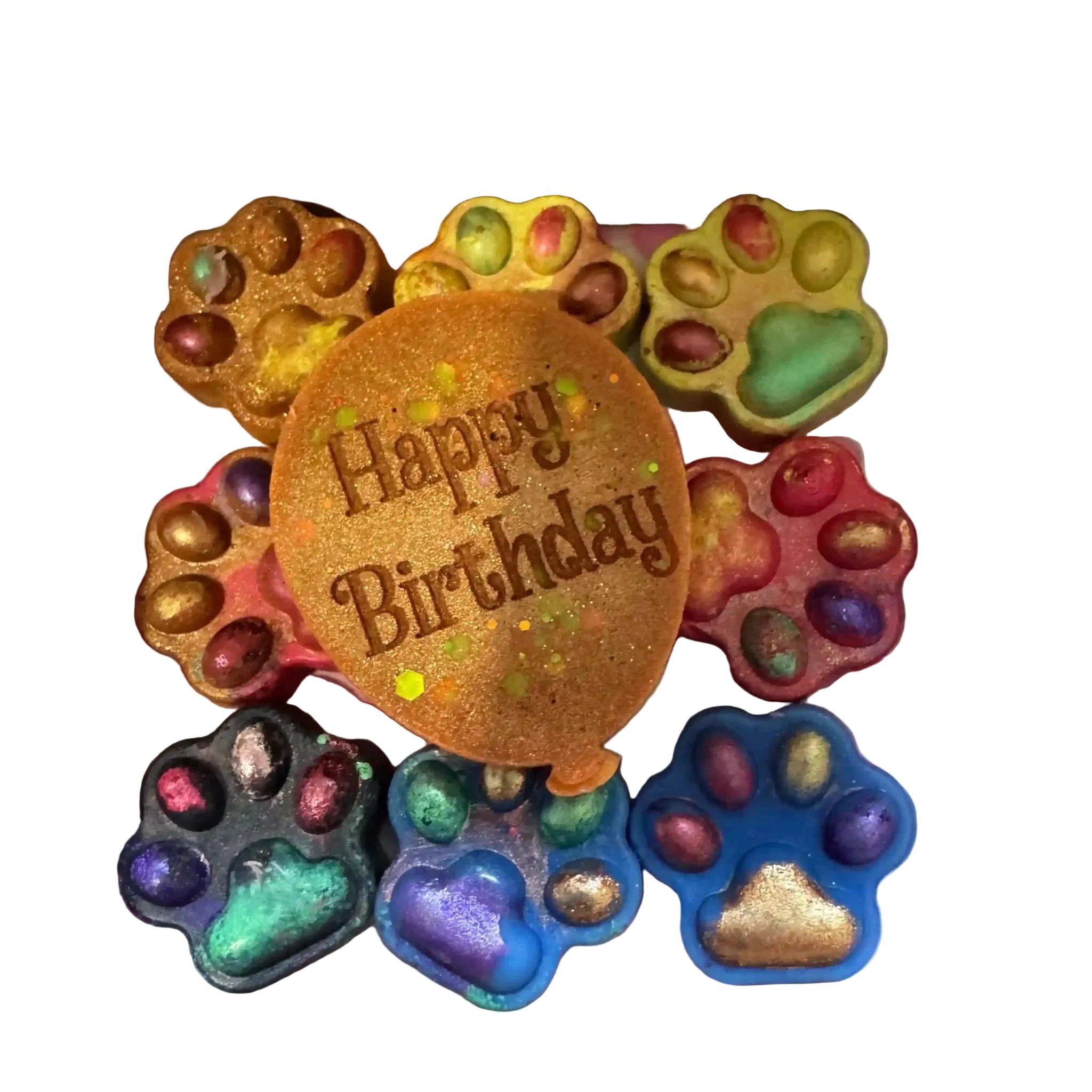 A gift box of colorful pet-shaped soaps with a central round soap that reads 'Happy Birthday' in brown lettering. The soaps are shaped like dog and cat paw prints in various colors including blue, green, purple, pink, yellow, and black, with metallic foil accents. scoopies wax melts