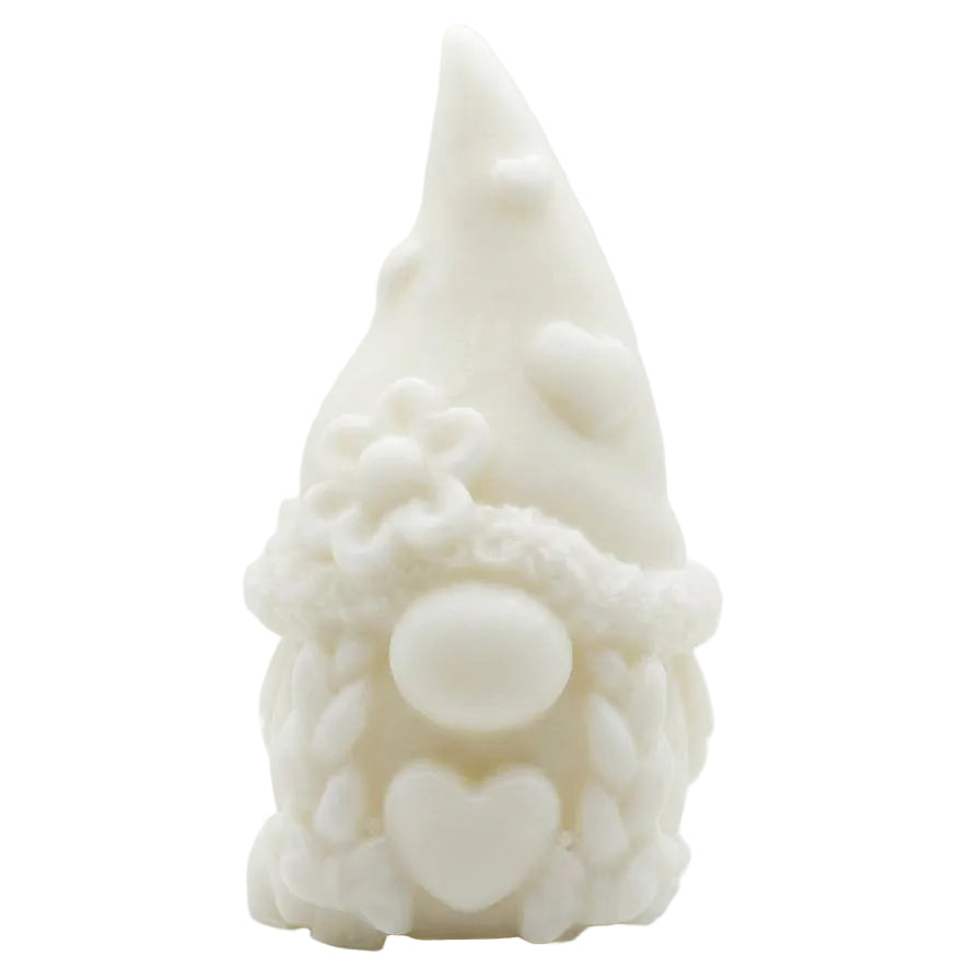 An unpainted white ceramic or clay gnome figurine with a pointed hat, textured beard, and heart details, set against a plain white background. candle
