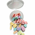 A clear plastic jar with its lid open, filled with pastel candy-like pieces and with several pieces spilled around it on a light gray surface. Text on the image reads 'this is a 1 oz pot'. WAX MELT