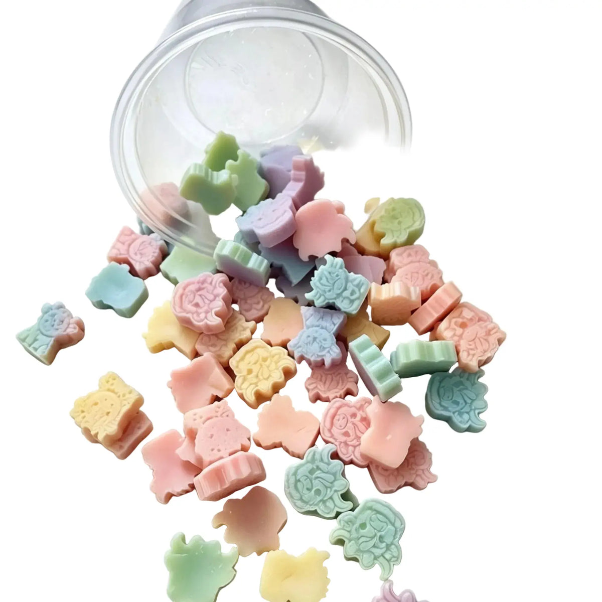 A clear plastic cup tipped over on a white background, spilling a mix of small pastel animal-shaped candies or soap pieces in pink, green, yellow, blue, and purple. WAX MELT SCOOPIES