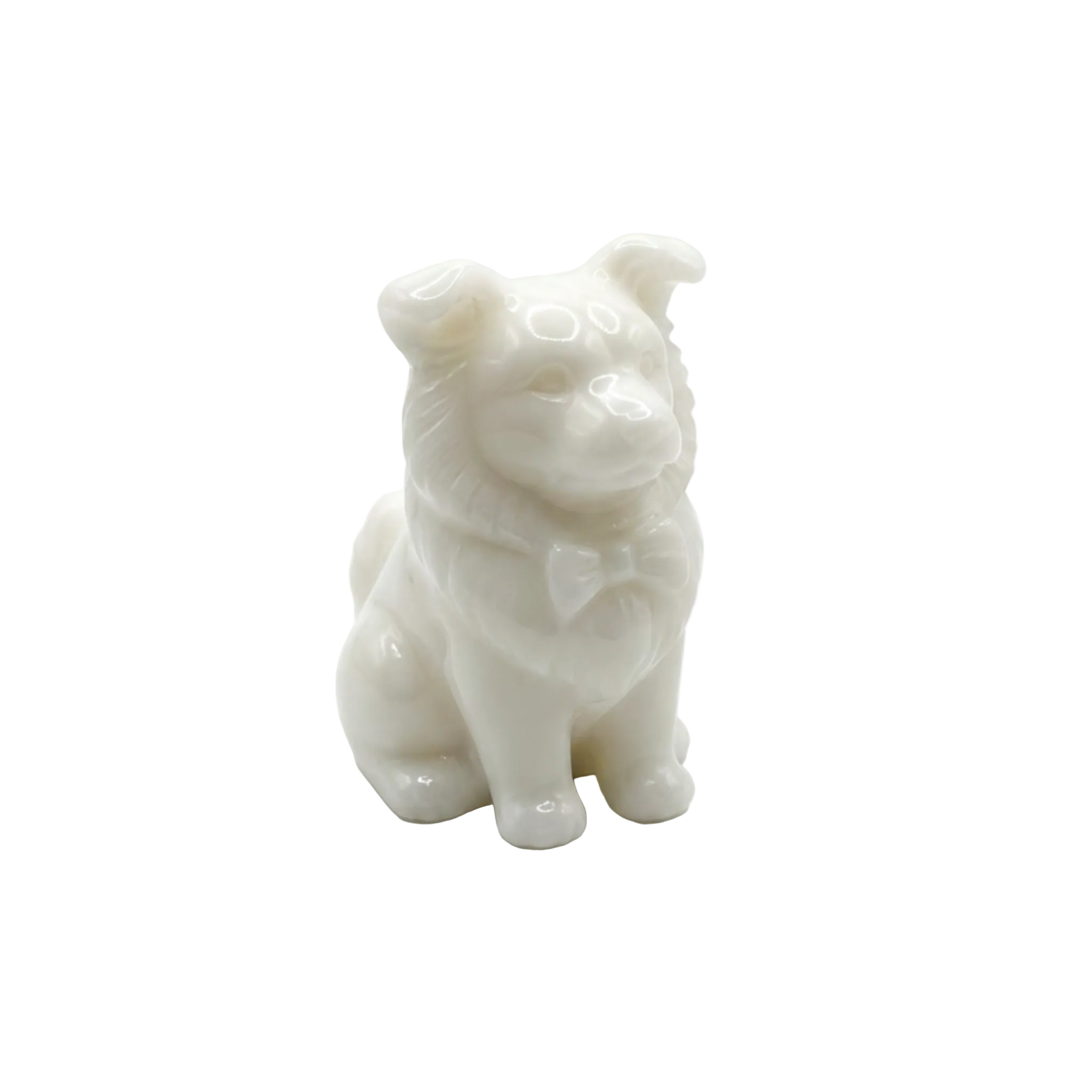 A small white candle of a dog with a bow tie, standing on a seamless light gray background. 