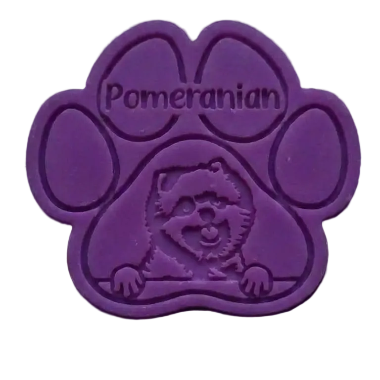 A purple paw-shaped wax meltfeaturing an embossed Pomeranian dog face and the word 'Pomeranian' on the upper pad, shown against a black background.