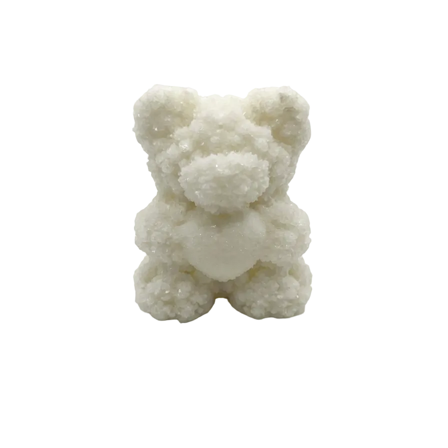 A small white teddy bear candle with a textured, crystalline or frosted surface, centered on a seamless light gray background.