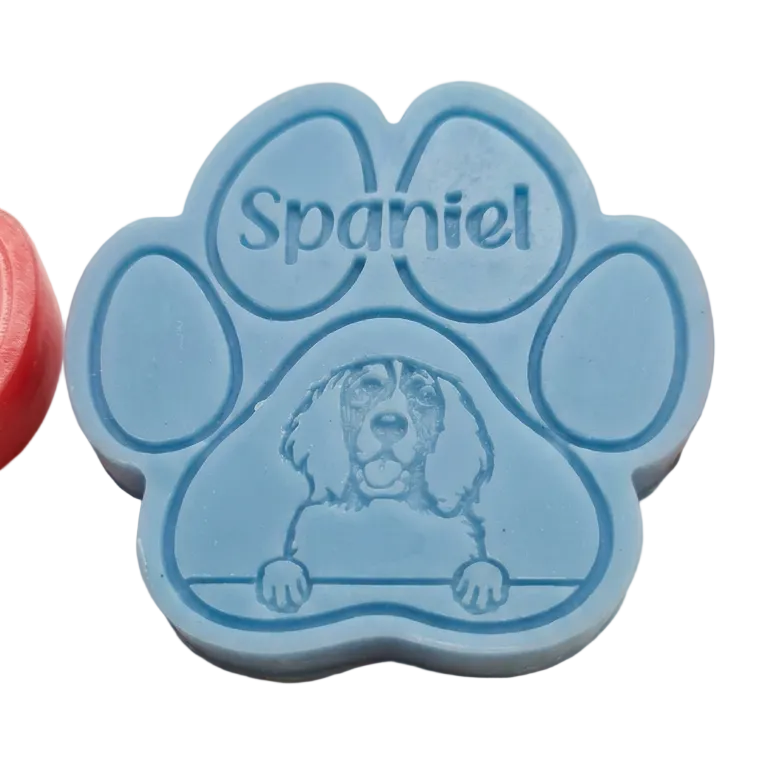A light blue paw-shapedWax Melt featuring an engraved dog illustration and the word 'Spaniel' on a plain light beige background.