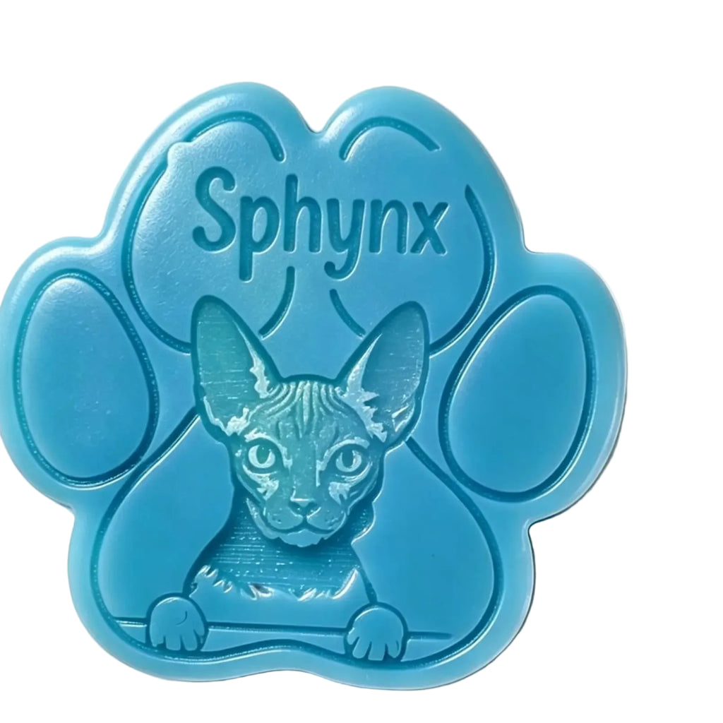 A blue paw-shaped WAX MELT featuring an embossed Sphynx cat face and the word 'Sphynx' on the top, photographed on a plain white background.
