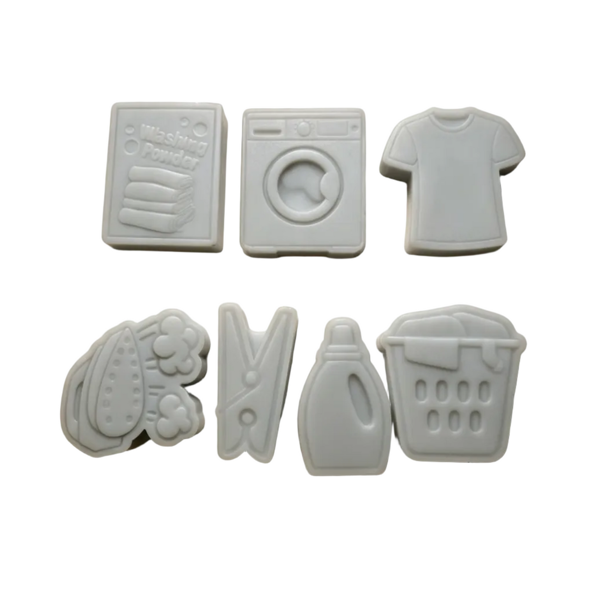 Six light gray laundry-themed wax melt pieces arranged on a beige background, including a washing powder box, washing machine, t-shirt, clothesline, detergent bottle, and laundry basket. A small 'Dola AI' watermark appears in the bottom right corner.
