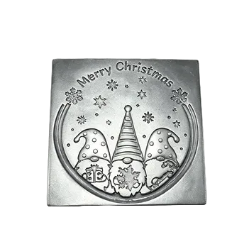 A square silver-toned metal Christmas wax melt featuring an engraved design of three gnomes under stars and snowflakes, with the text 'Merry Christmas' at the top, shown on a white checkered background.
