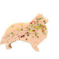 A dog-shaped WAX MELT in a pale peach-beige color, decorated with multicolored glitter and small confetti, shown on a plain white background.
