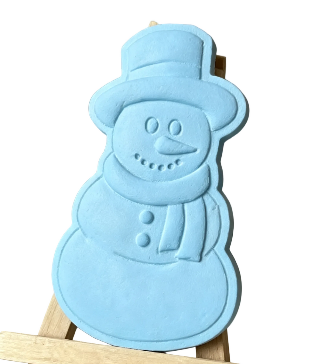 A light blue snowman-shaped decorative wax melt  displayed on a small wooden easel against a neutral indoor background.